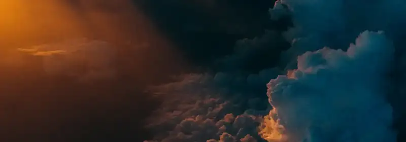 Dunkle Wolken, durch die orangefarbenes Sonnenlicht fällt (Symbolbild)